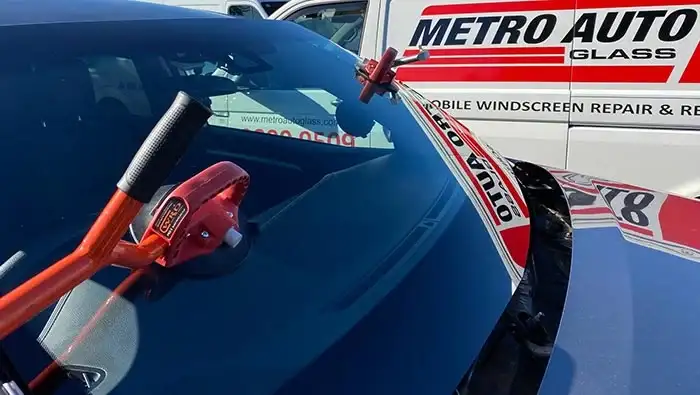 Technician performing windscreen replacement on a vehicle